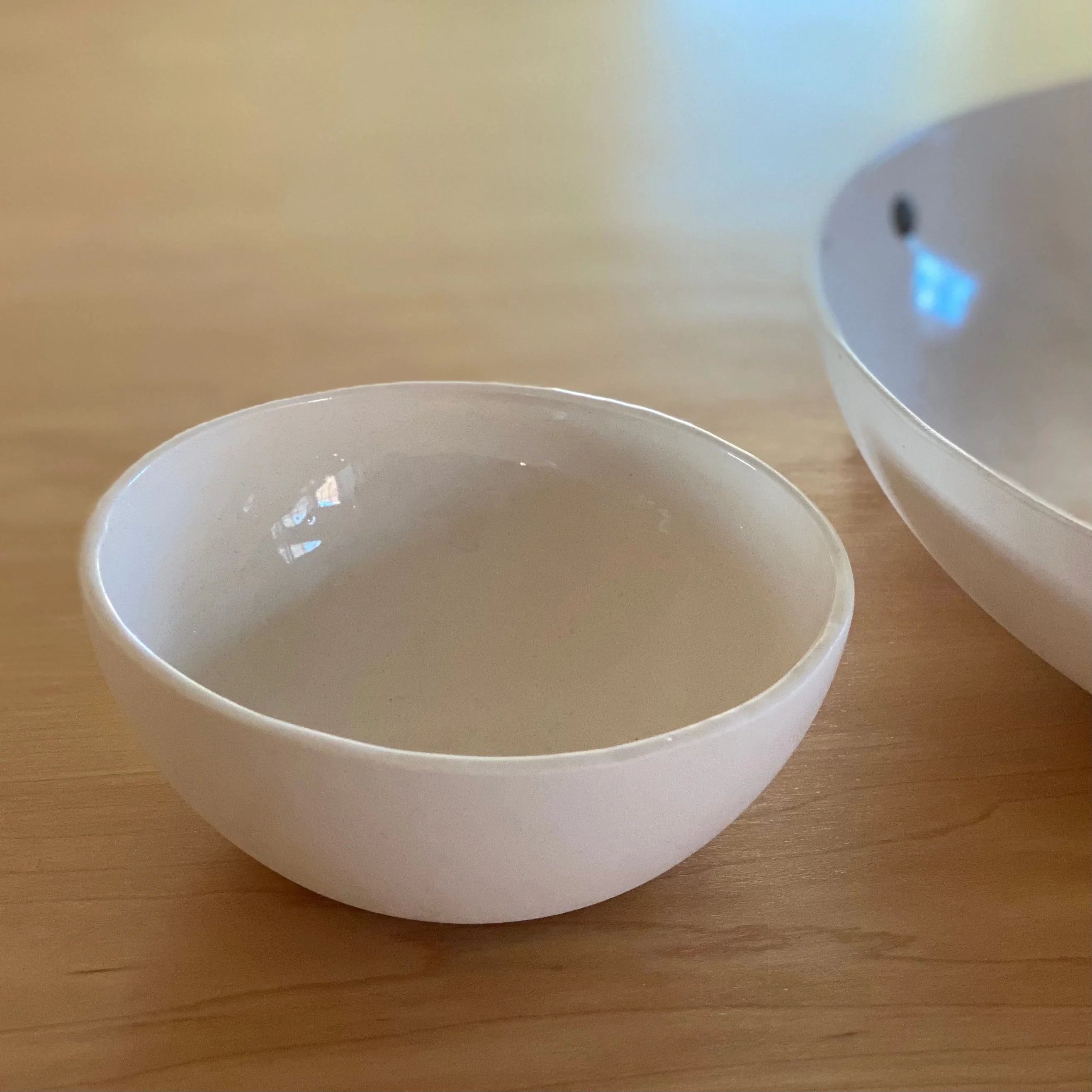 Handmade white ceramic bowl on light wood surface, modern minimalist Qu!rk Boutique decor