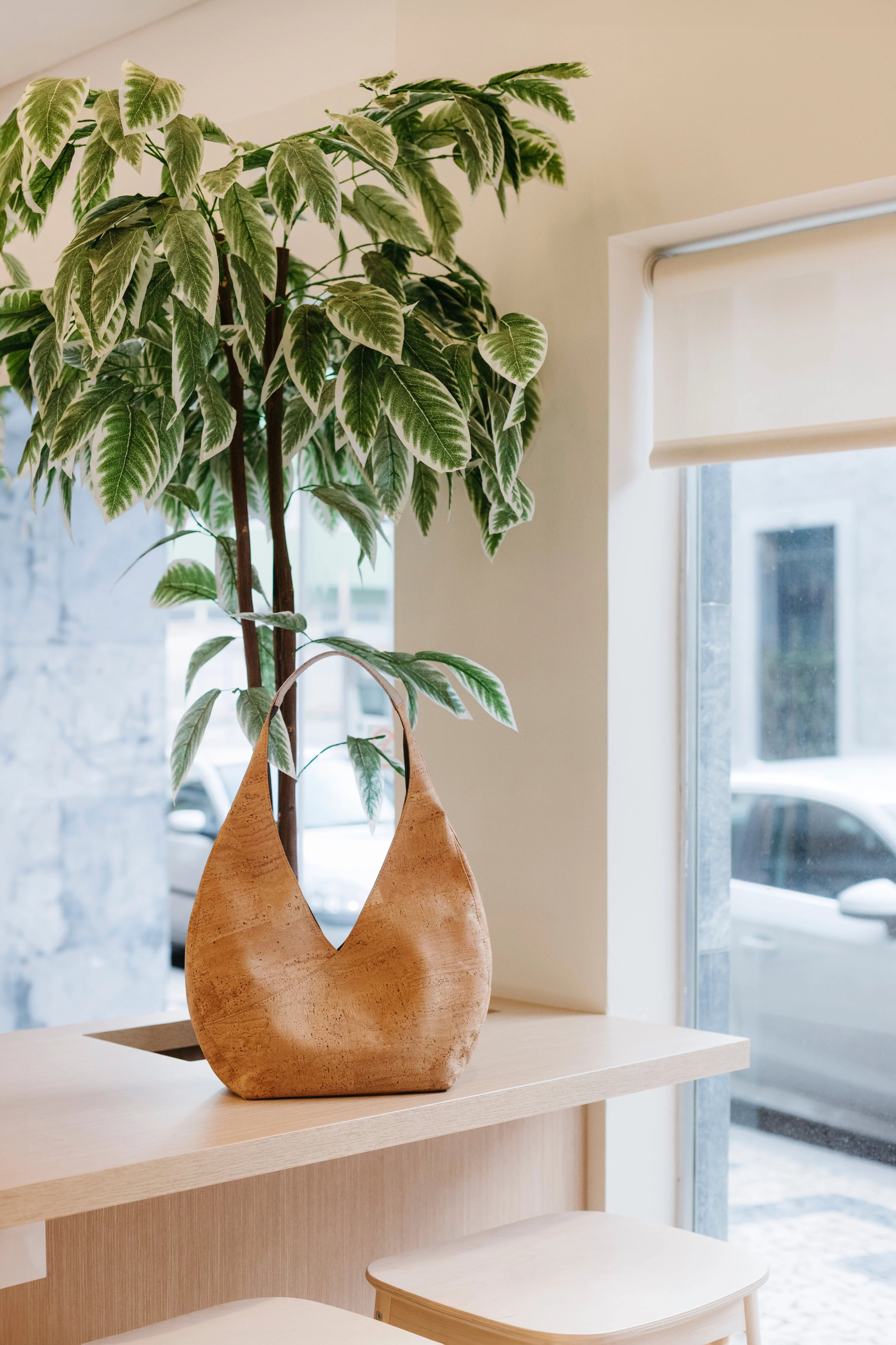 Natural cork tote bag on light wood table by indoor plant in Qu!rk Boutique eco-friendly setting