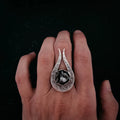 Hand wearing unique silver abstract open-ended ring against black background