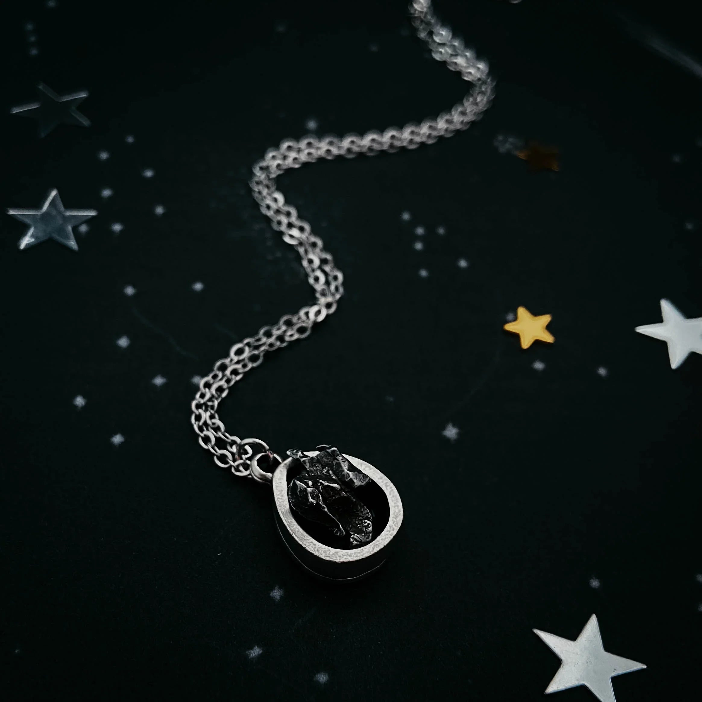 Silver cosmic necklace with a black stone pendant on starry background, Qu!rk Boutique gift
