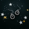 Teardrop cosmic earrings with black stones on starry background from Qu!rk Boutique