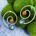 Artist-designed cosmic spiral earrings with Earth and sun motifs on green moss, Qu!rk Boutique