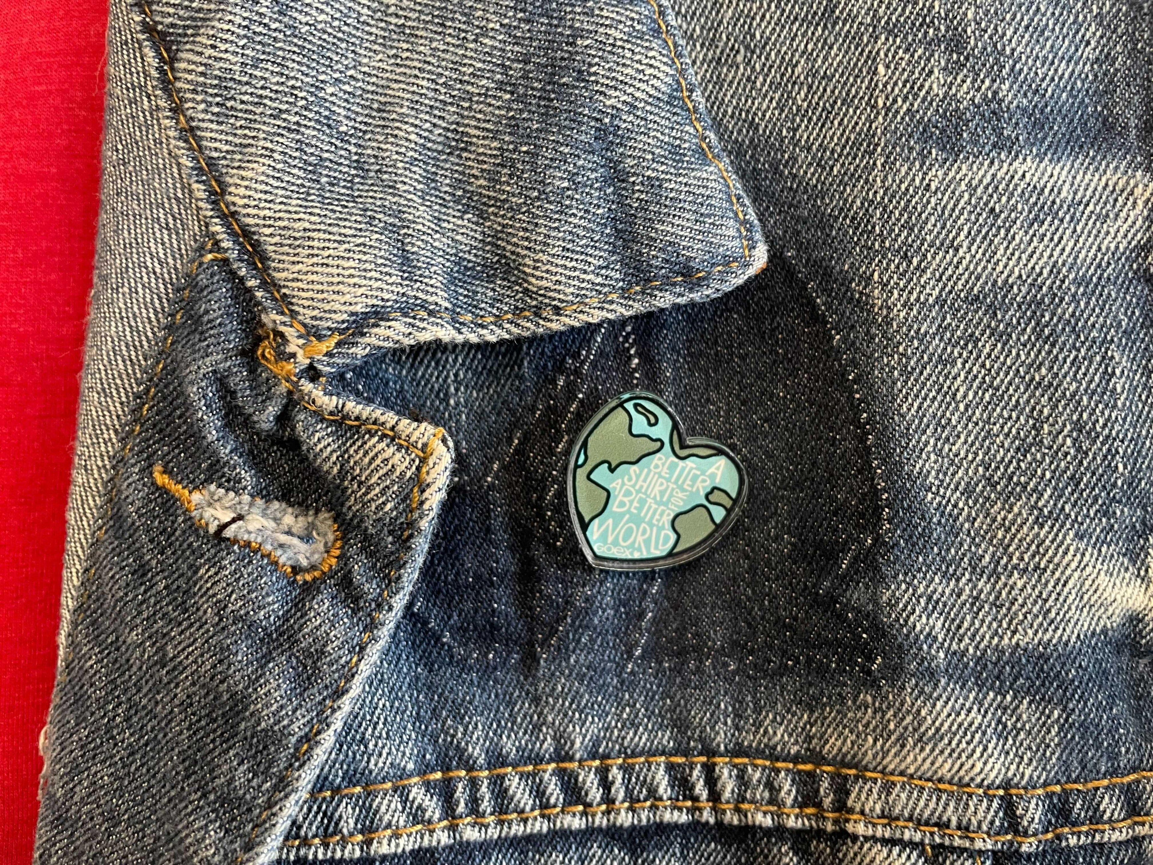 Eco-friendly enamel pin shaped like Earth on blue denim jacket at Qu!rk Boutique