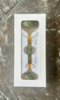Jade facial massage roller in white gift box with gold accents on stone background