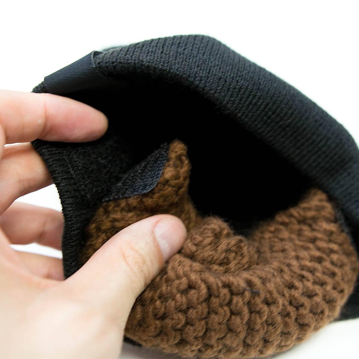 Hand holding black knit beanie with soft brown fleece lining inside