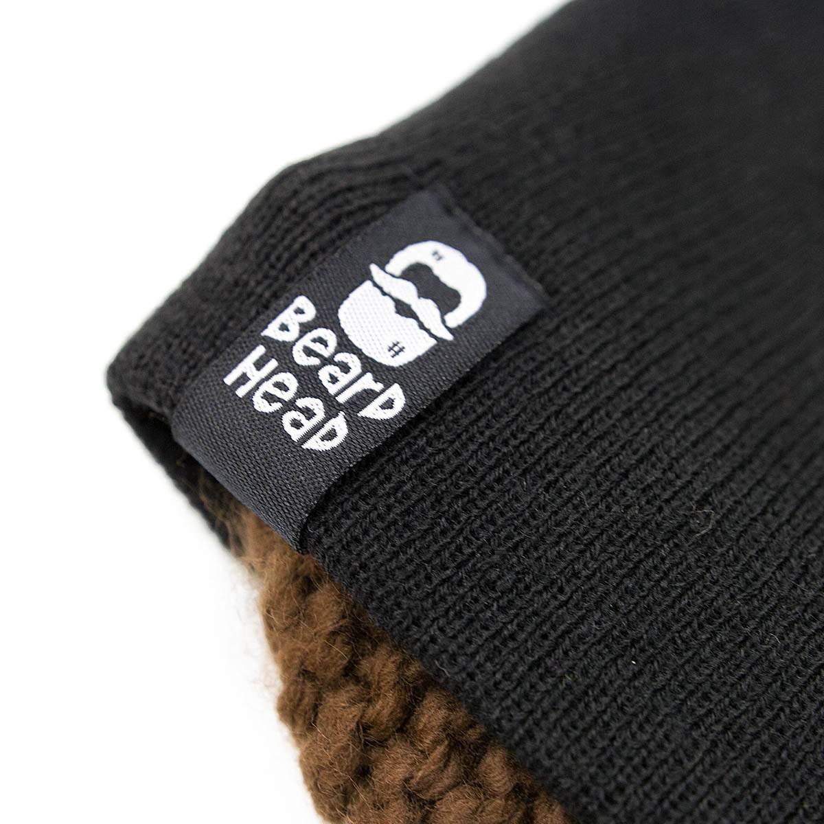Close-up of black knit beanie label with white Bear Head logo and text on brown knit fabric