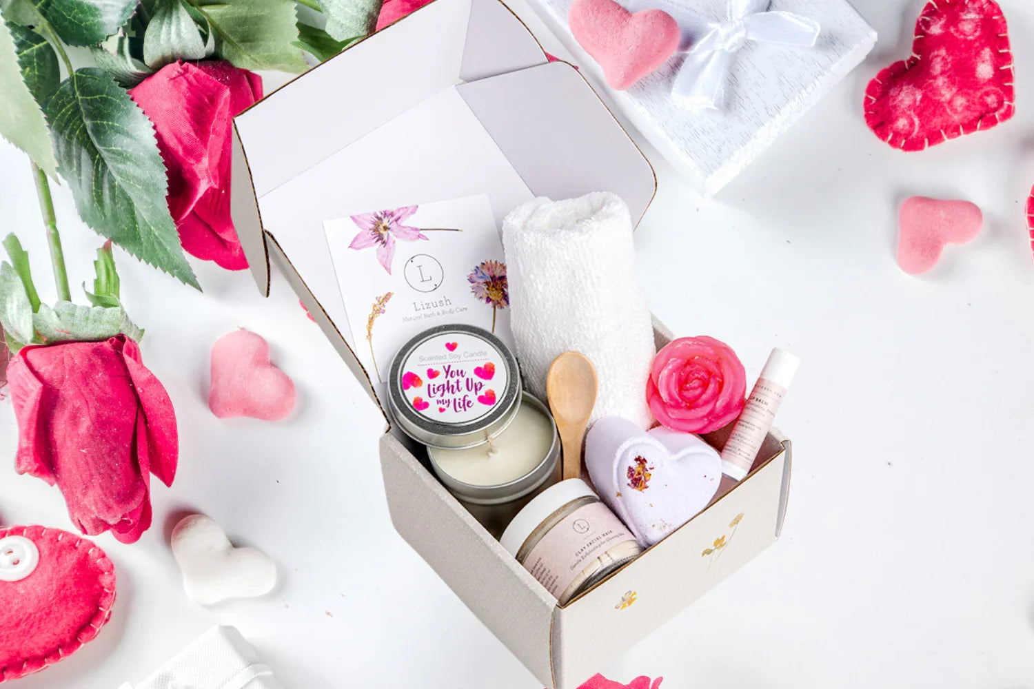 Gift box with spa items including candle, towel, wooden spoon, lip balm, and heart-shaped bath bomb