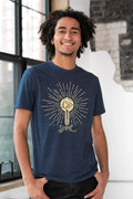 Smiling person wearing a navy unisex tee with 'Let Your Light Shine' sunburst graphic, Qu!rk Boutique