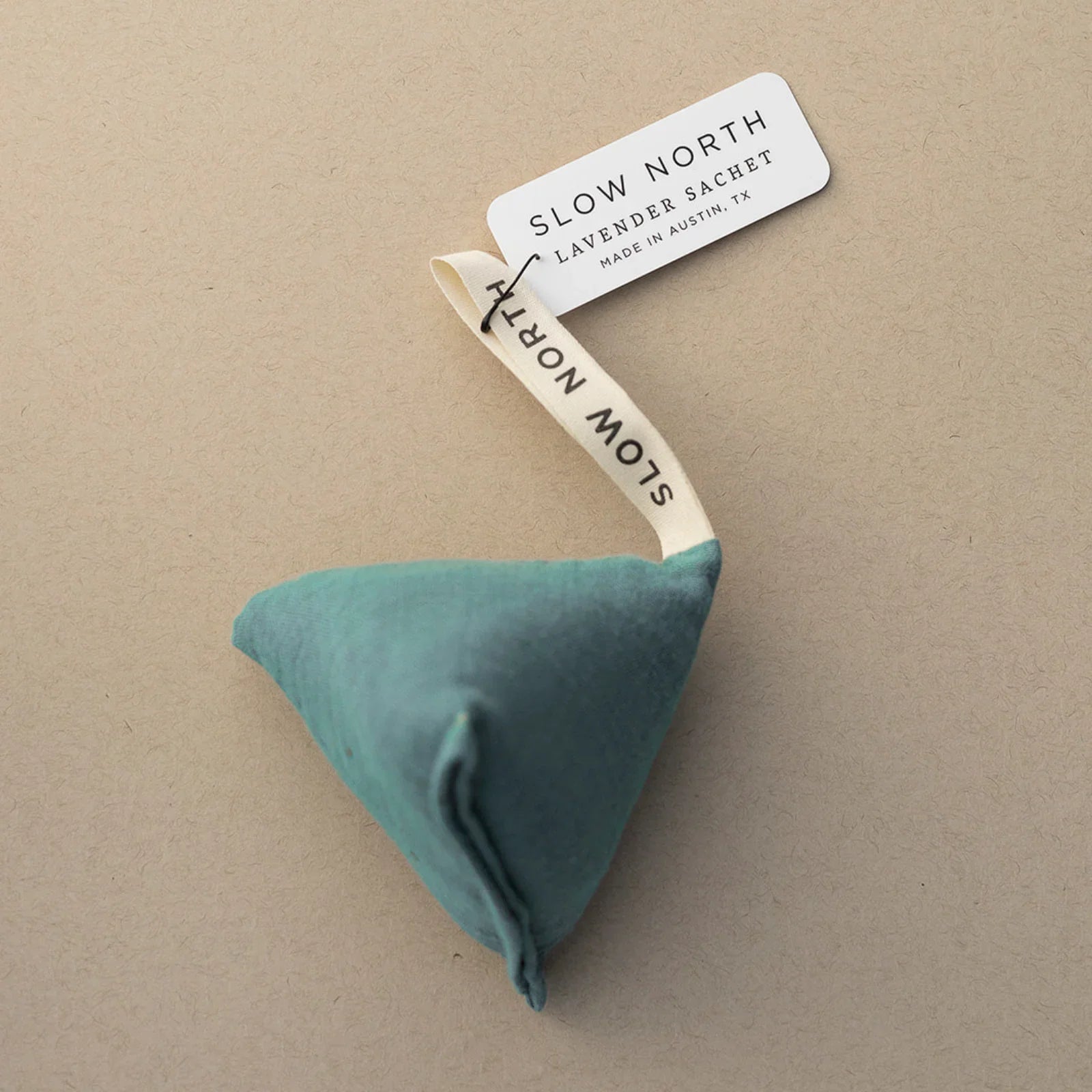 Teal Lagoon Lavender Sachet by Slow North with branded fabric loop and label, on beige background