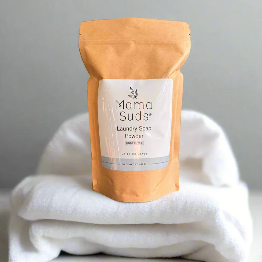 Mama Suds laundry soap powder pouch on folded white towels, eco-friendly cleaning product