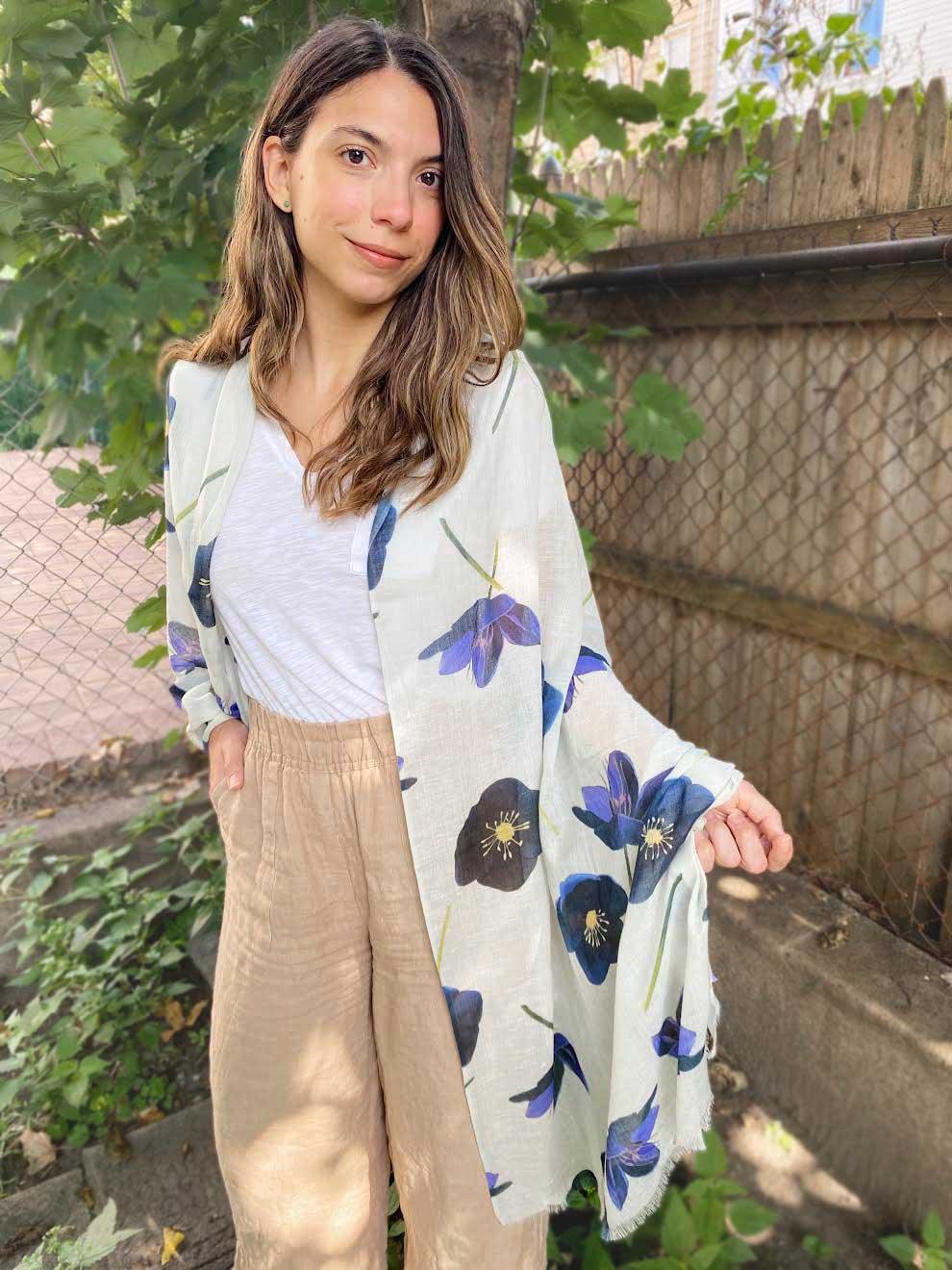 Woman outdoors wearing a white scarf with large blue and black hellebore flower print