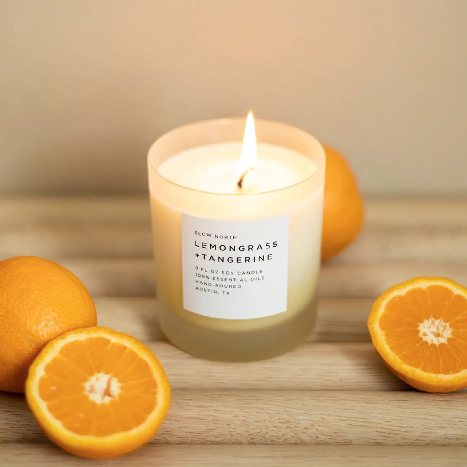 Lemongrass tangerine soy candle in glass jar with tangerine halves on wood table