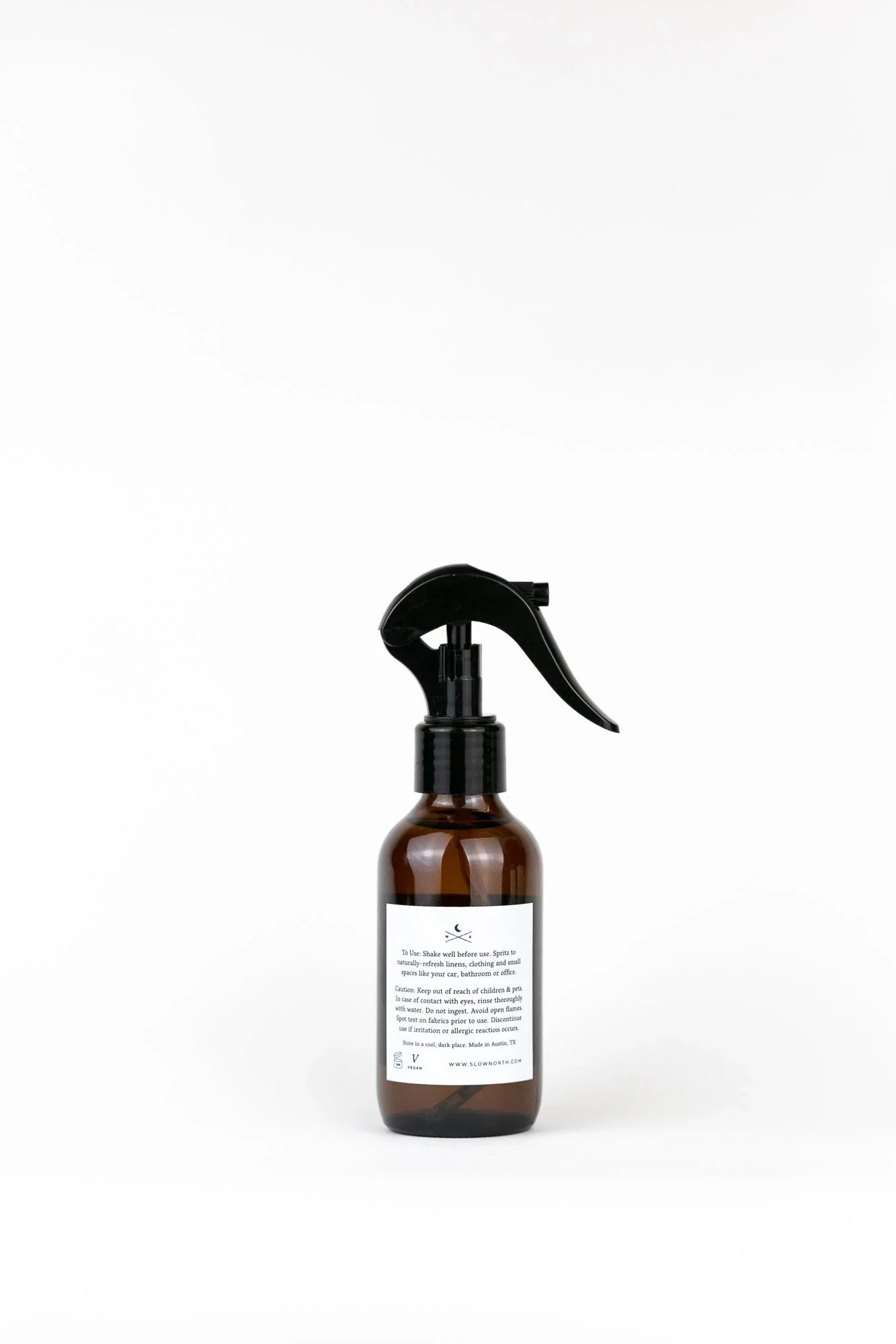 Amber glass linen spray bottle with black trigger, minimalist label, on white background at Qu!rk Boutique