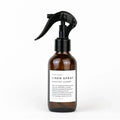 Amber glass spray bottle of Slow North Linen Spray Midnight Garden with black trigger nozzle