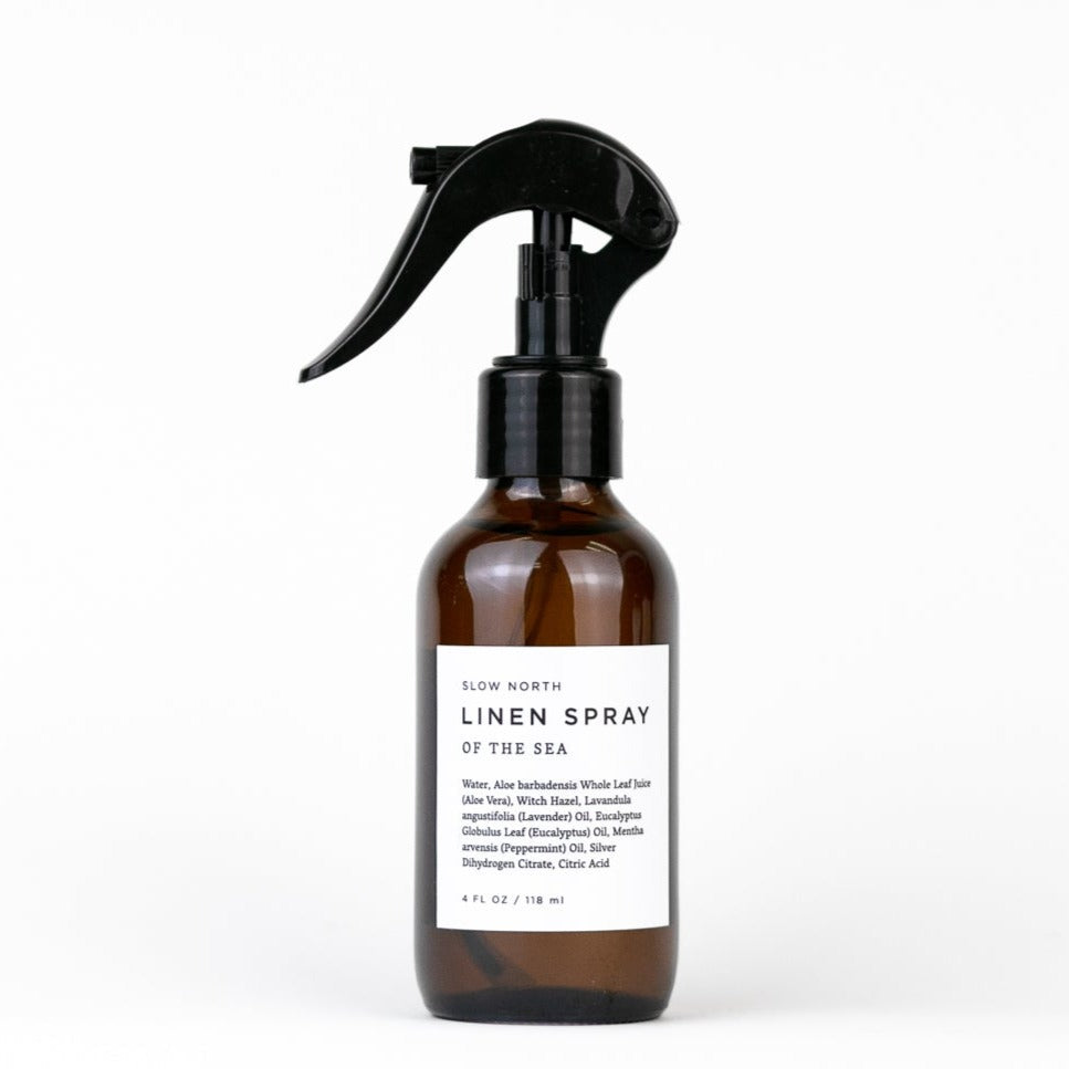 4 oz amber linen spray bottle with black trigger labeled Slow North Linen Spray of the Sea