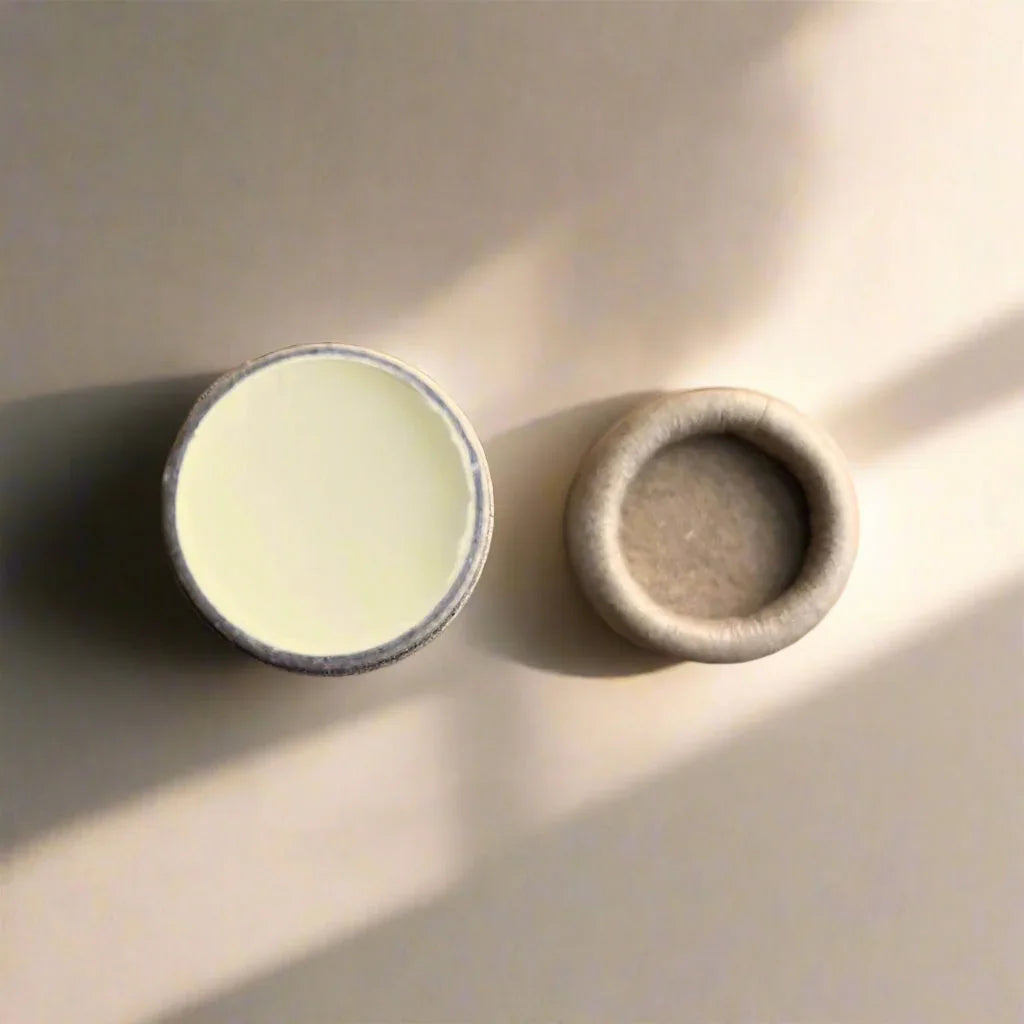 Open eco-friendly lip balm tube with cap, shown on neutral surface at Qu!rk Boutique