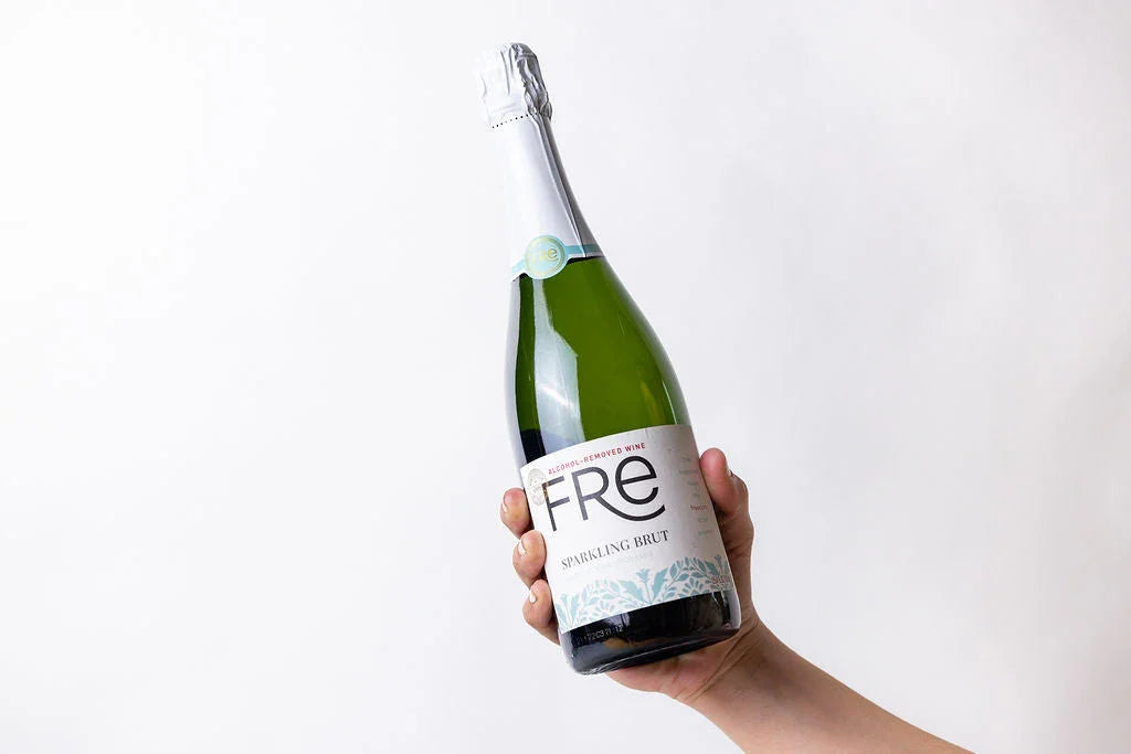 Hand holding a bottle of Fre alcohol-removed sparkling brut wine against a white background