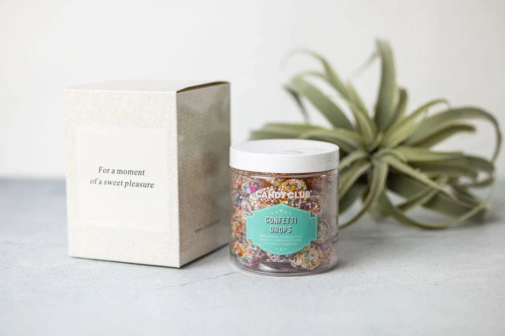 Colorful confetti drops candy jar and gift box on a light surface at Qu!rk Boutique