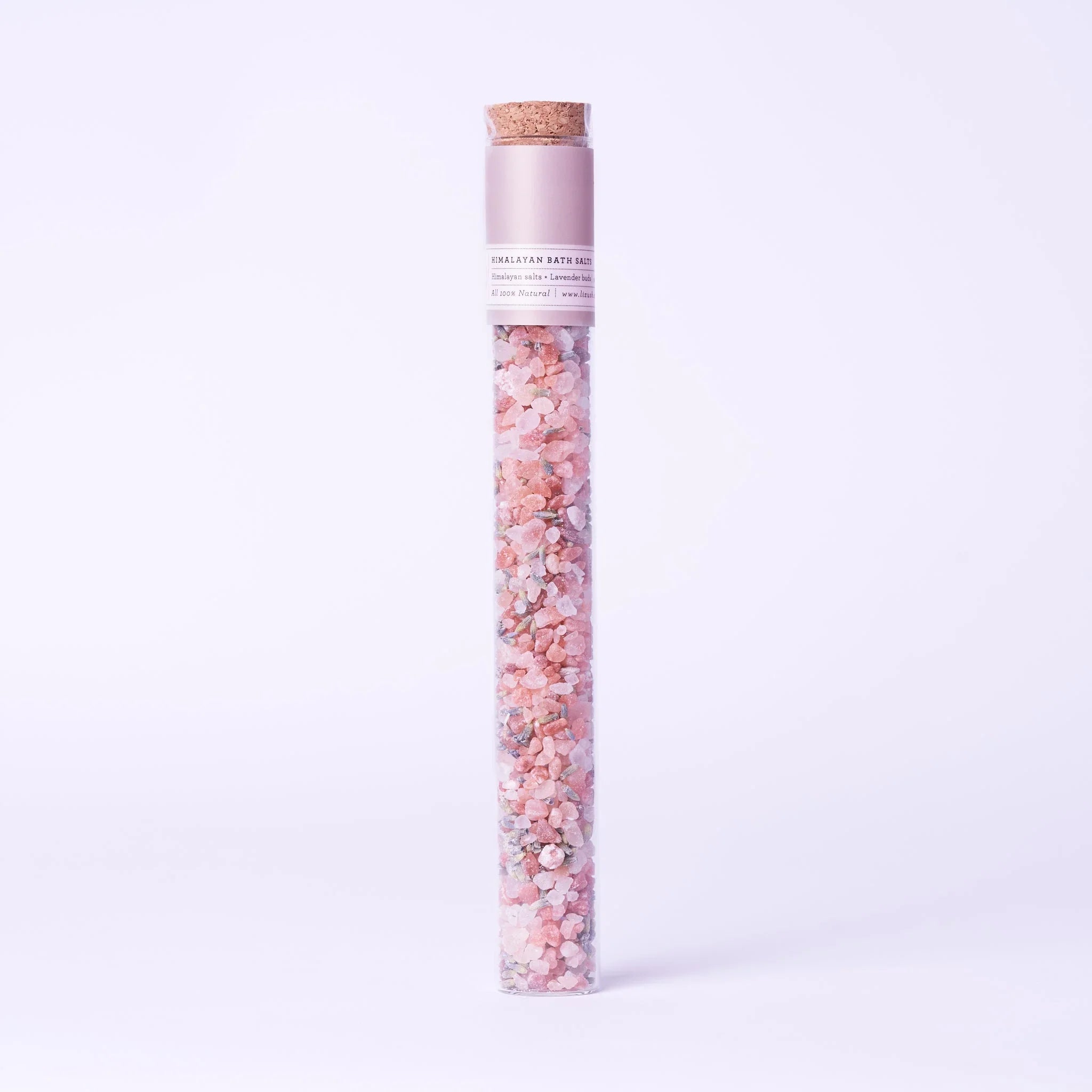 Tall clear glass tube with cork stopper filled with pink Himalayan bath salts and lavender buds