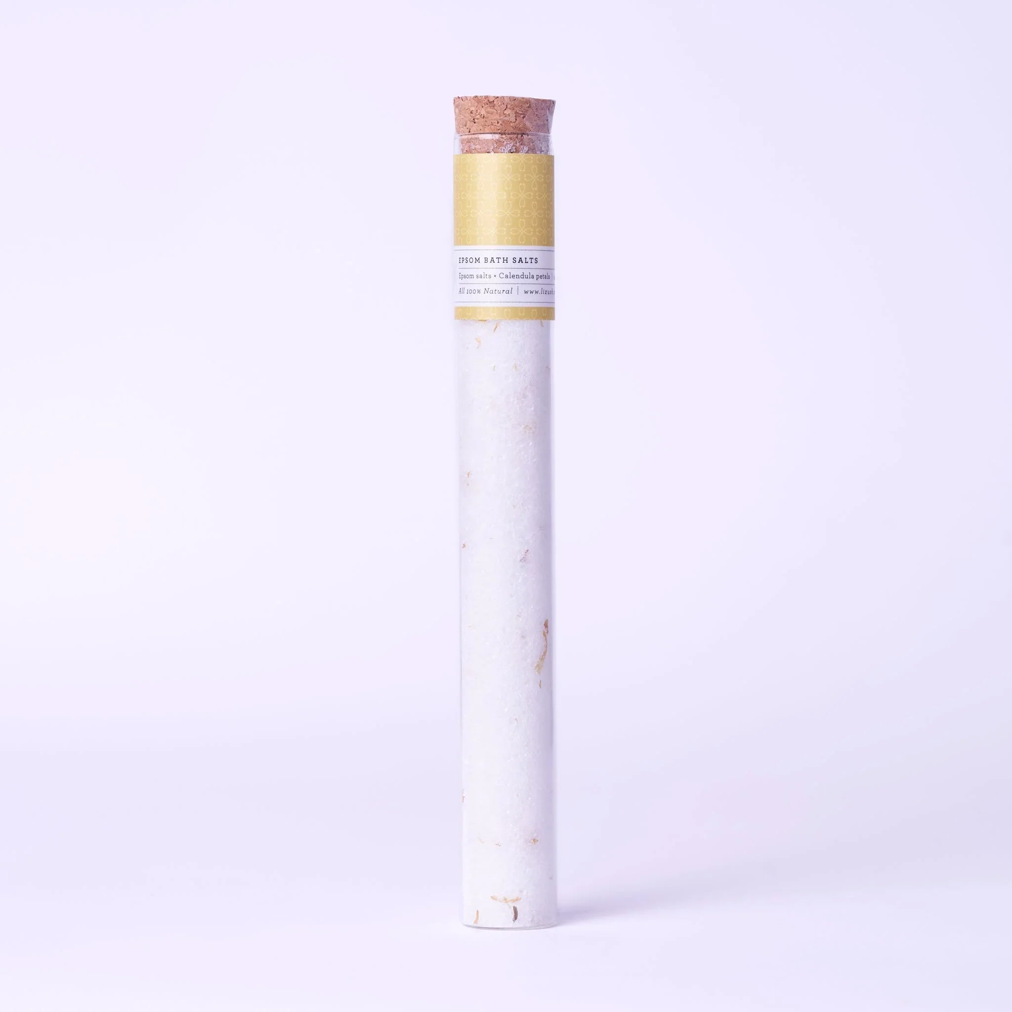 Tall glass tube with cork containing white Epsom bath salts with calendula petals and a yellow label