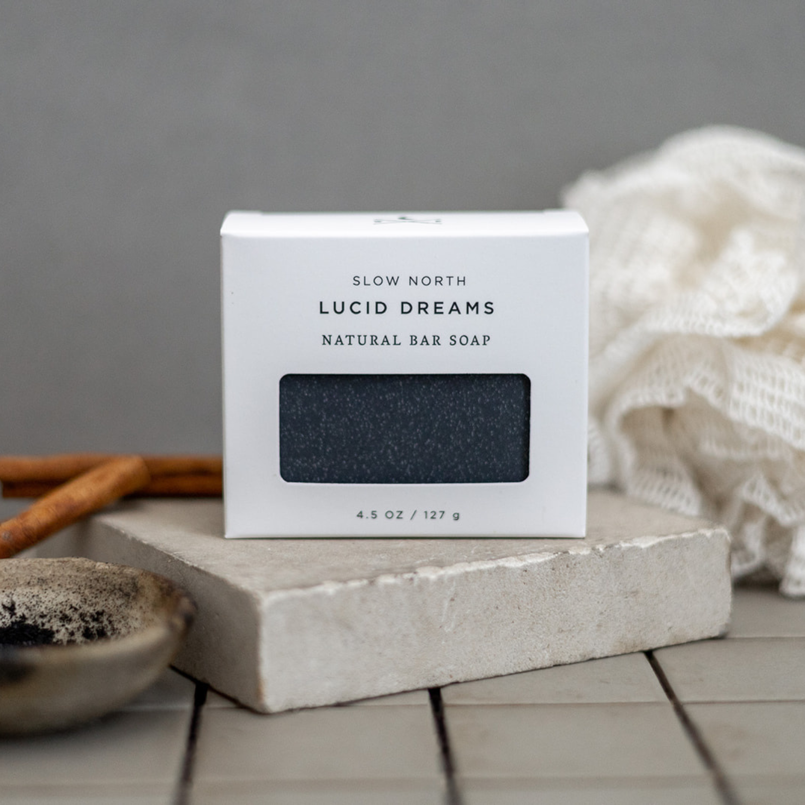 Slow North Lucid Dreams natural bar soap in white box on stone slab with textured cloth and cinnamon sticks