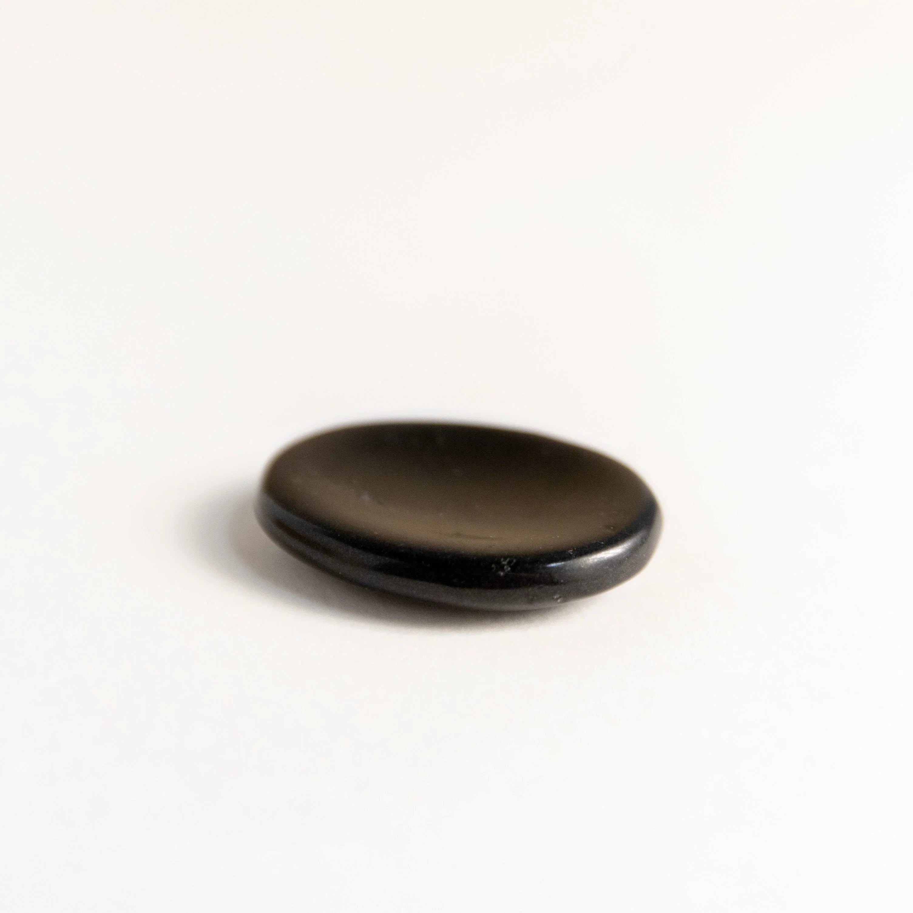 Small smooth polished black obsidian stone on white background
