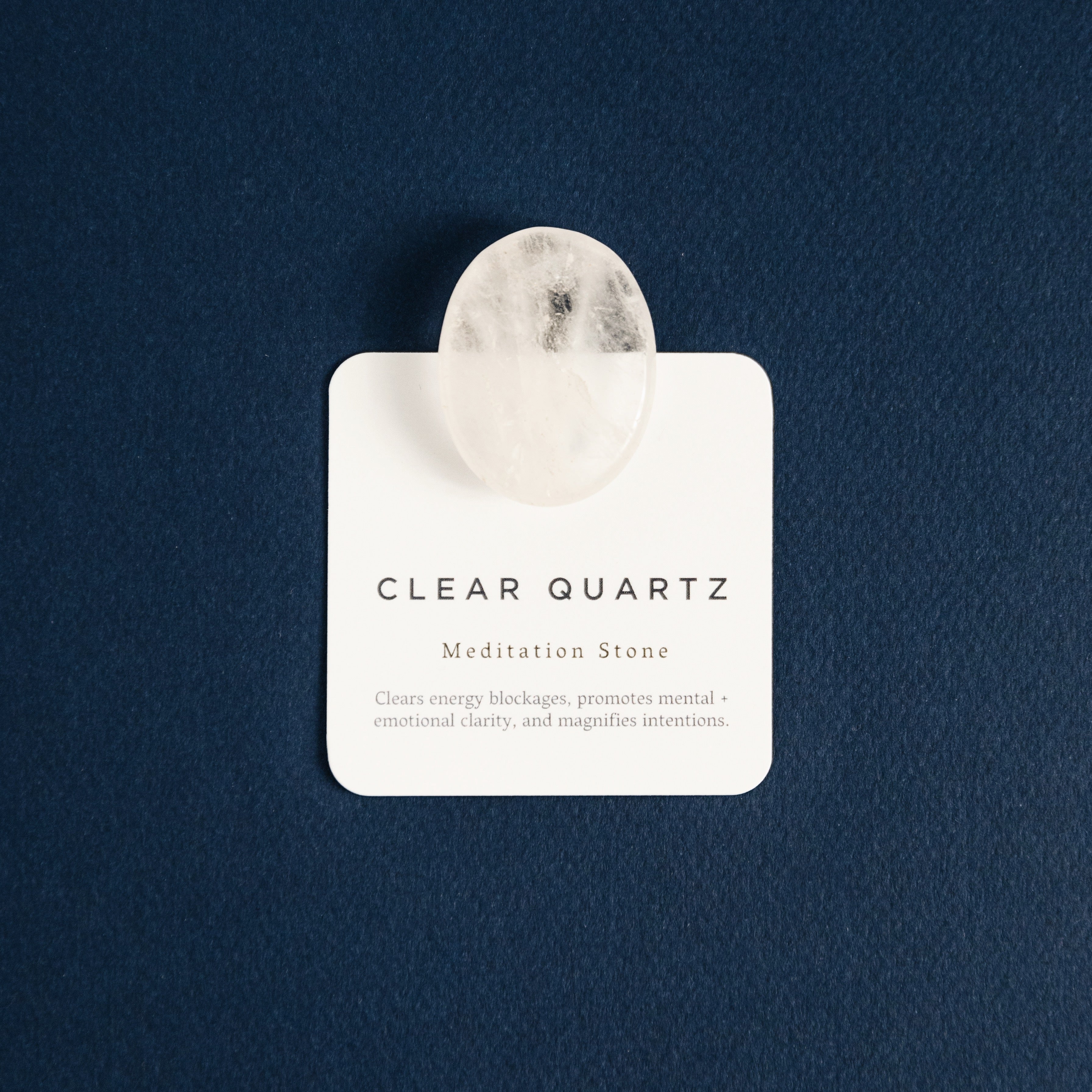 Clear quartz meditation stone on card describing its energy clearing and clarity benefits