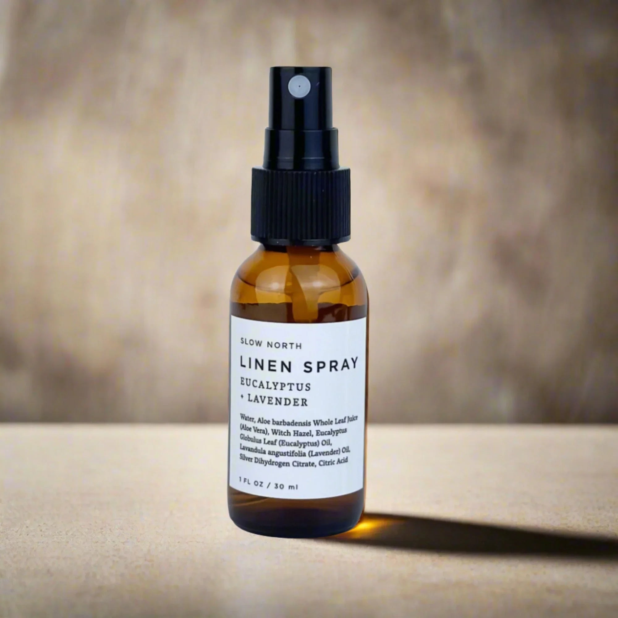 Amber glass bottle of Slow North Eucalyptus Lavender Linen Spray on neutral background at Qu!rk Boutique.