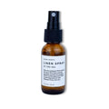 Amber glass bottle of Slow North Linen Spray Of The Sea with black spray top on white background