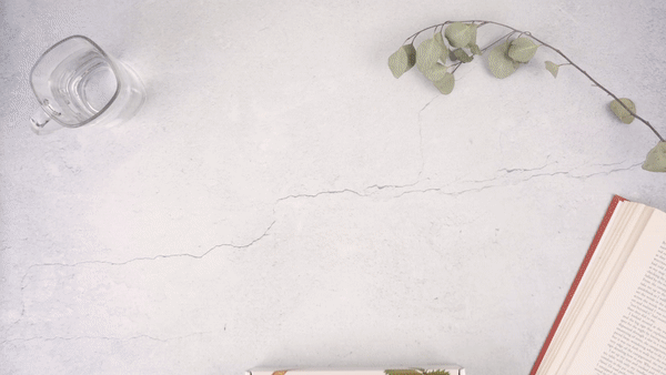 Men's natural grooming skincare gift box with products, eucalyptus branch, glass of water, and open book on white surface