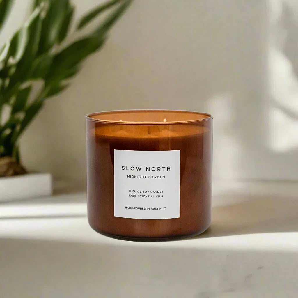 Slow North Midnight Garden 17 oz soy candle with essential oils in brown glass jar on white surface
