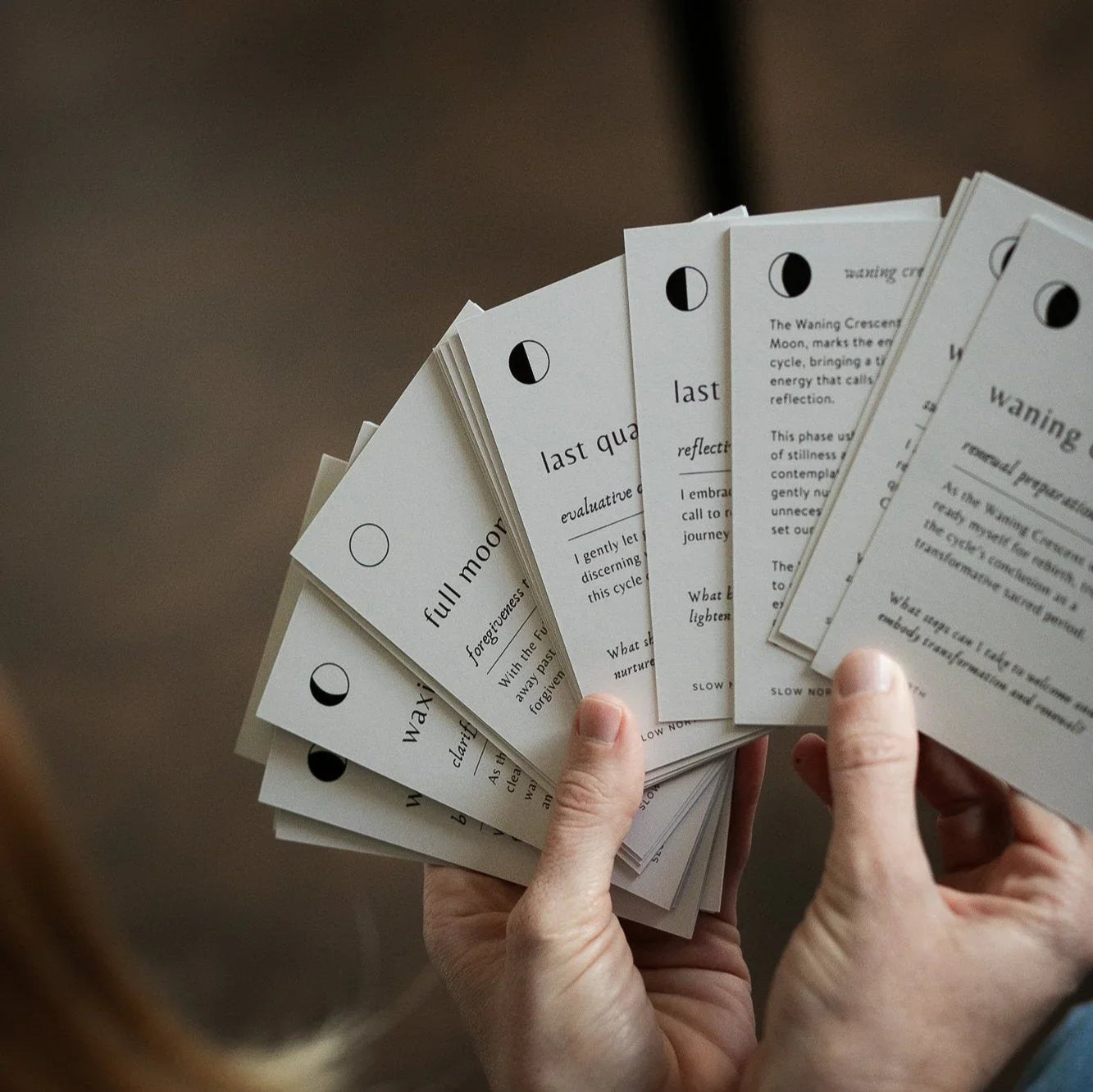 Hand holding a fan of educational moon phase cards with descriptions and illustrations