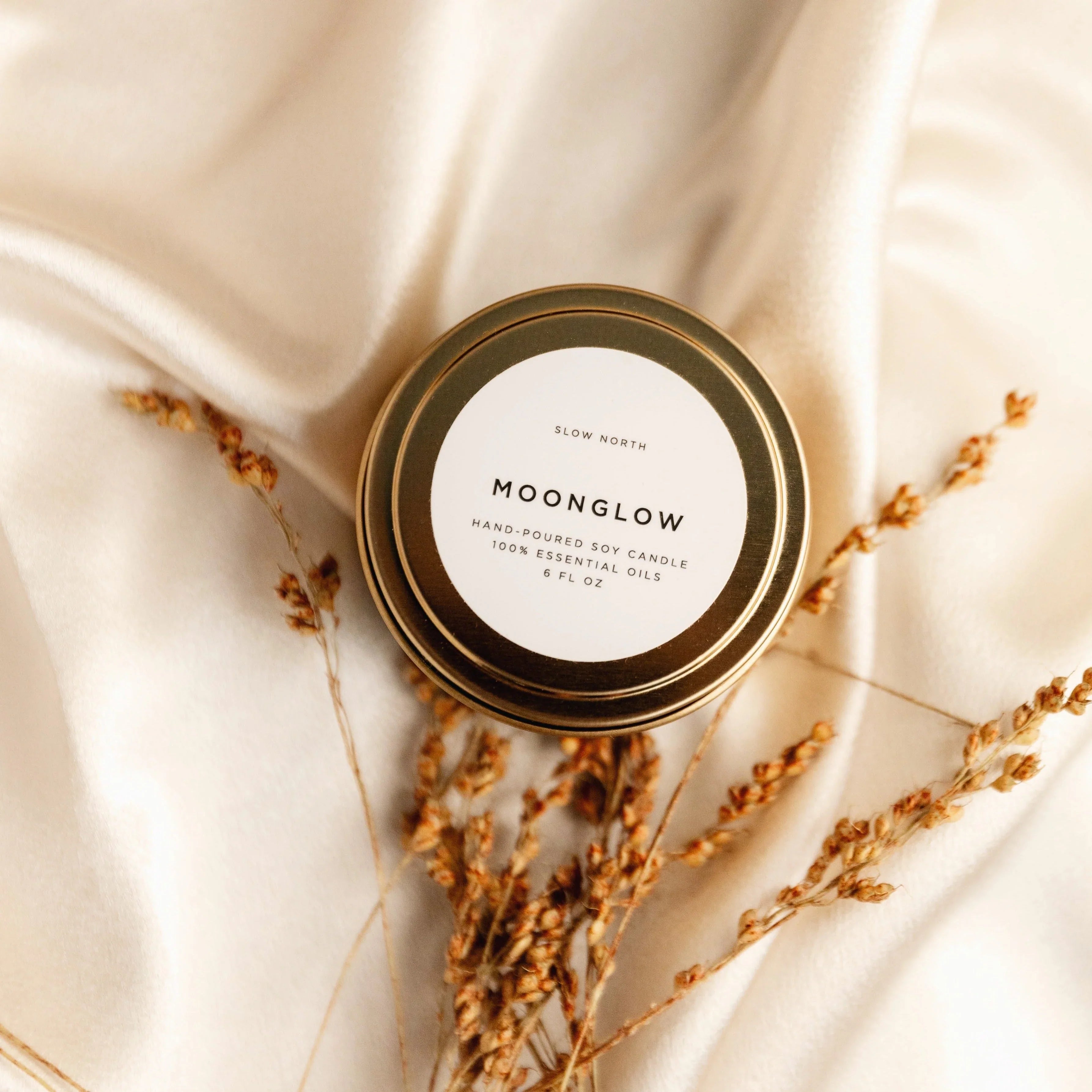 Moonglow travel tin soy candle on beige satin with dried floral accents, Qu!rk Boutique gift