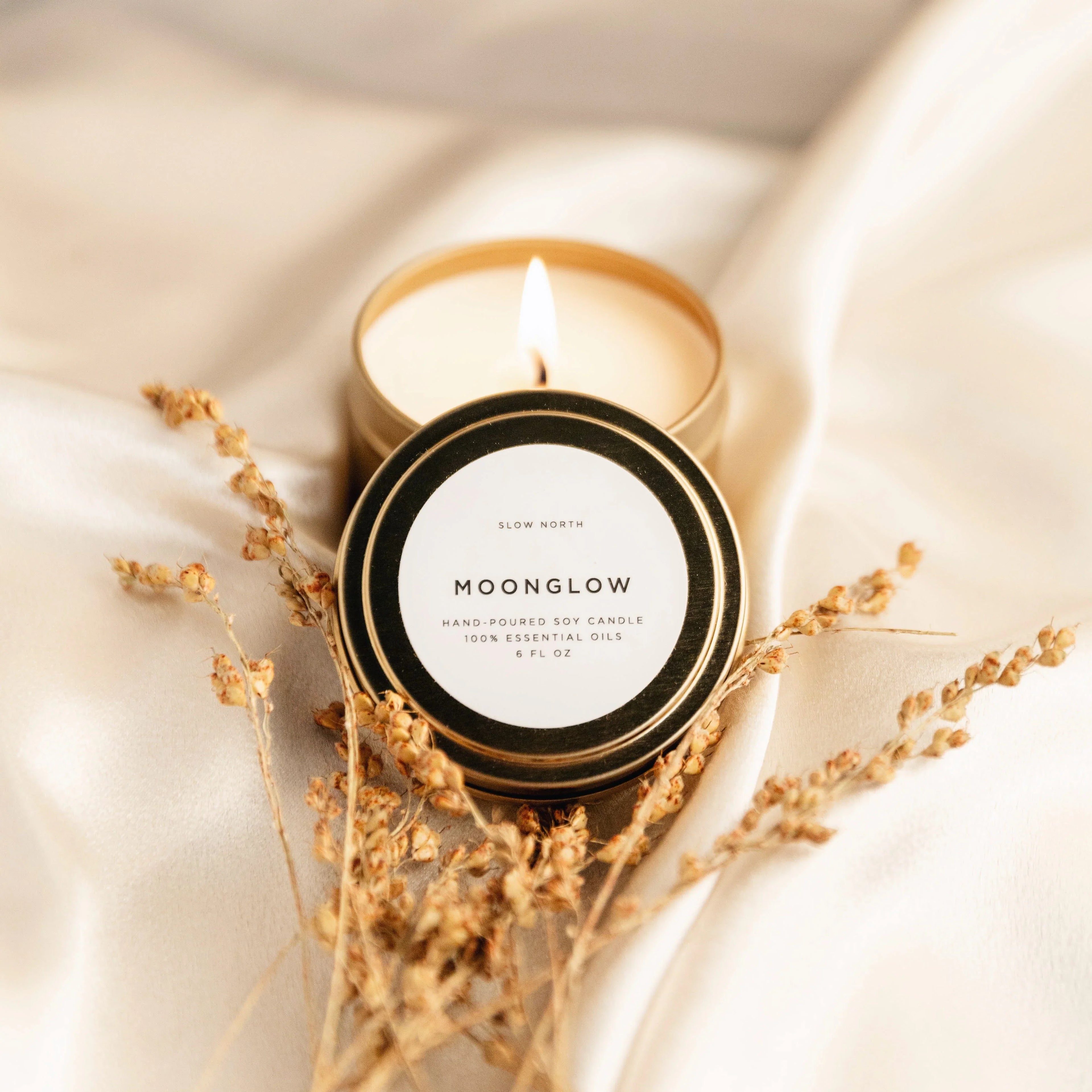 Moonglow hand-poured soy candle tin on cream fabric with dried flowers, Qu!rk Boutique gift
