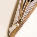 Close-up of a white and tan zippered cork wallet with gold hardware from Qu!rk Boutique