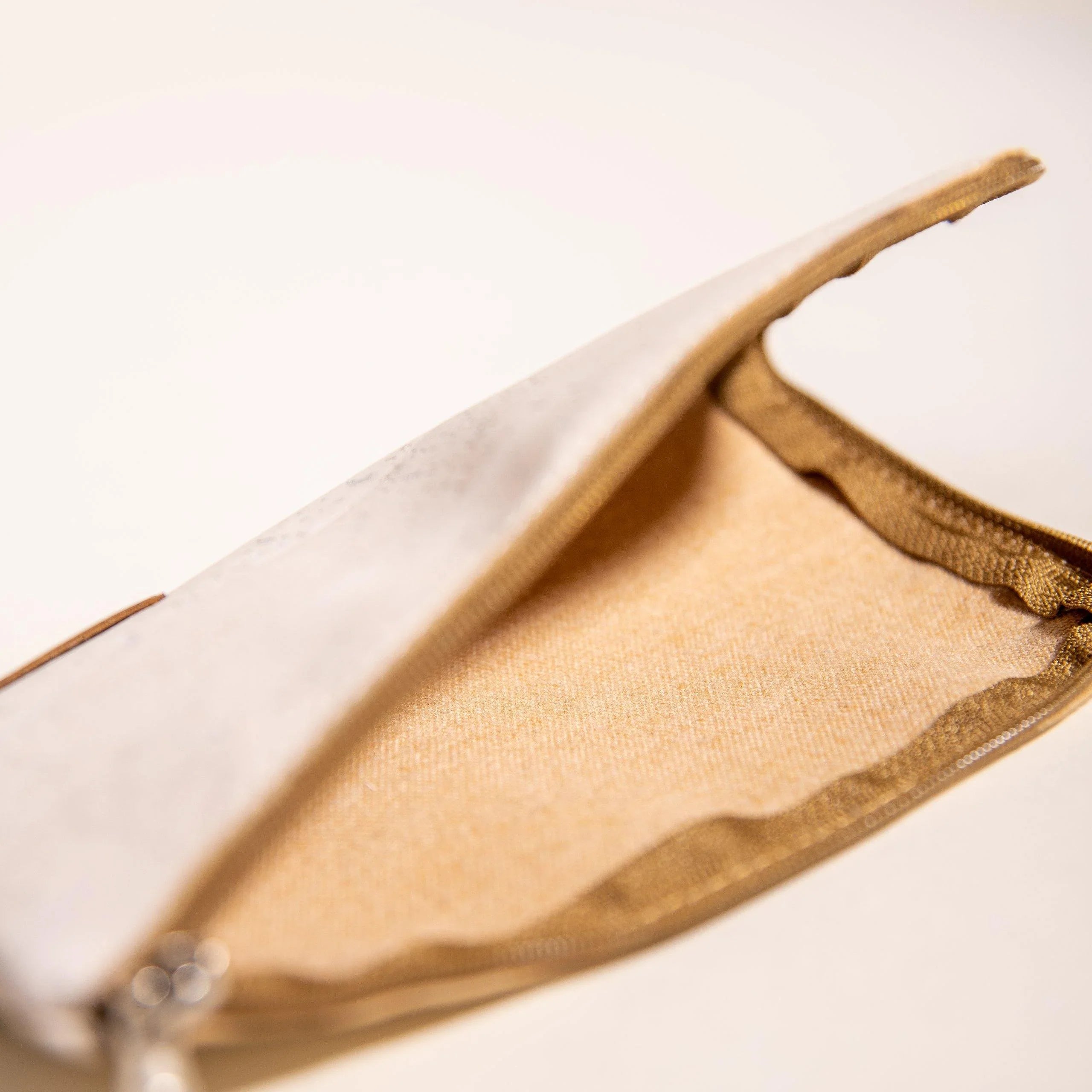 Open beige zippered pouch with gold lining from Qu!rk Boutique, shown on neutral background.