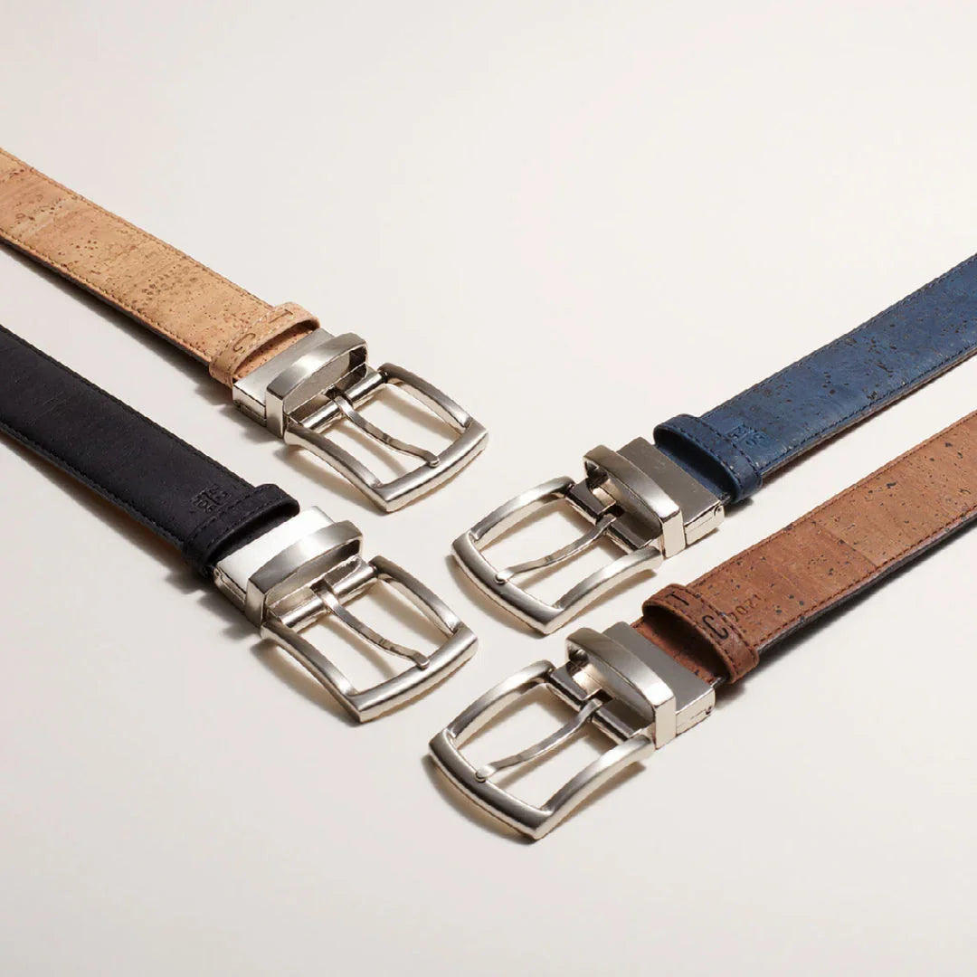 Four sustainable vegan leather belts in tan, black, blue, and brown with silver buckles