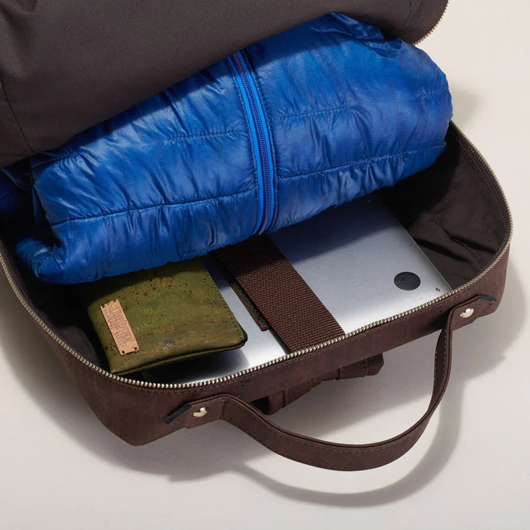 Brown bag with green wallet, blue puffer jacket, and laptop, Qu!rk Boutique style.