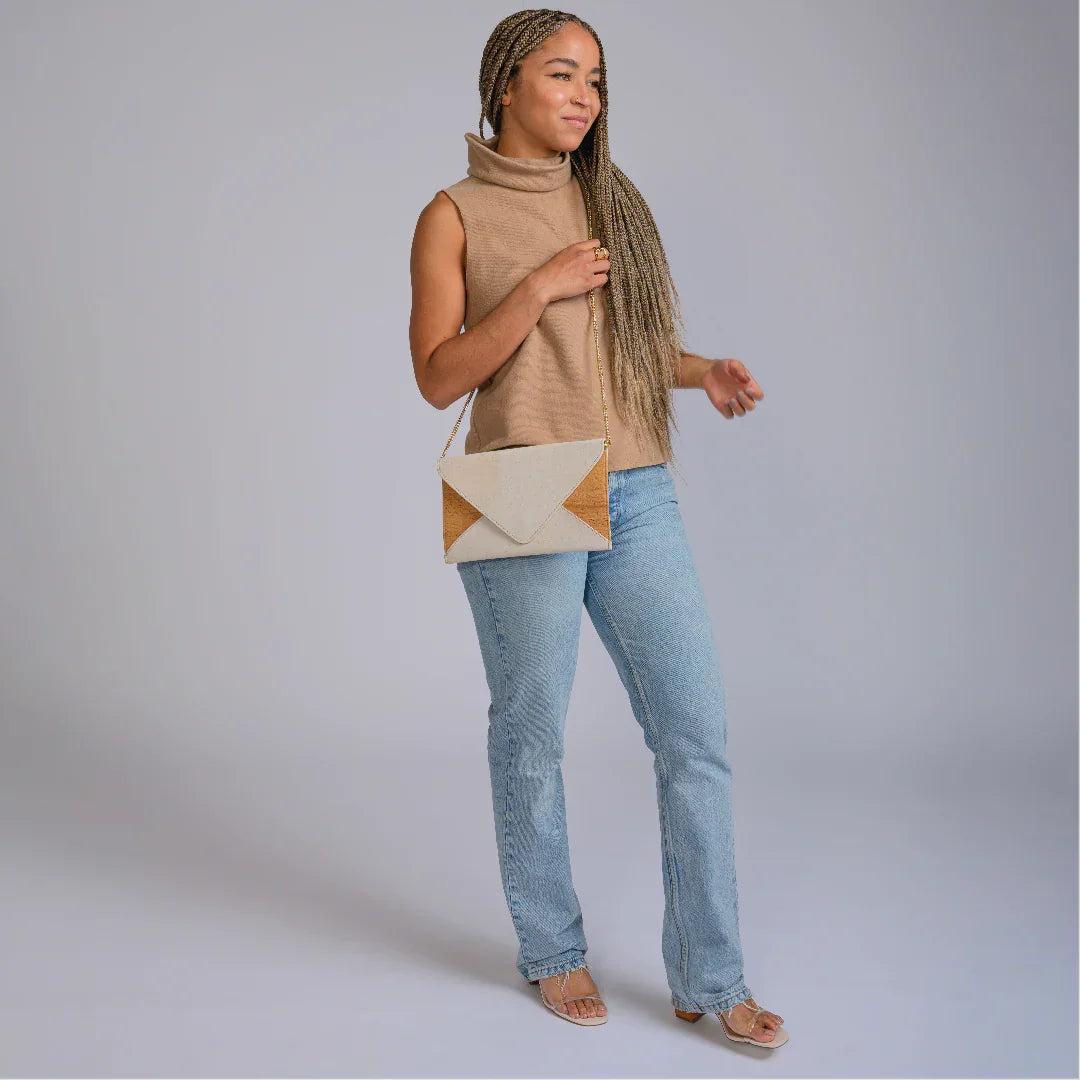 Woman wearing a tan sleeveless turtleneck, jeans, and a geometric crossbody bag at Qu!rk Boutique