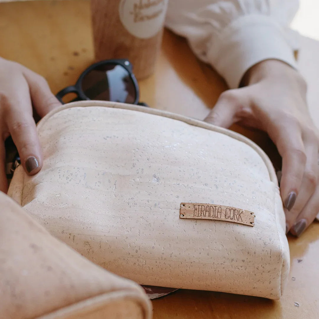 Ethically sourced cork cosmetic bag with Teradia Cork label, sunglasses, and coffee on table