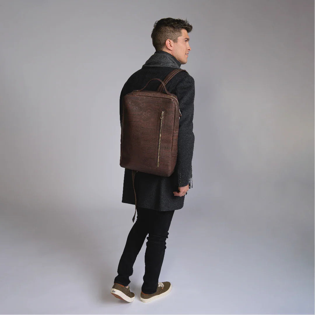 Man in dark coat wearing a brown cork backpack from Qu!rk Boutique on a studio backdrop