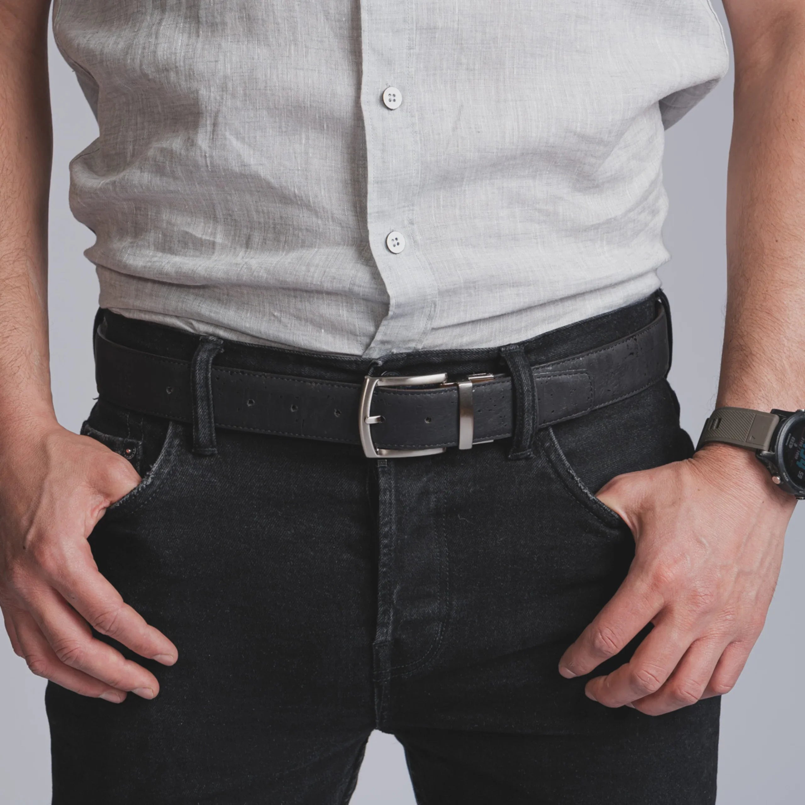 Man wearing black leather belt, black jeans, and a light grey shirt from Qu!rk Boutique