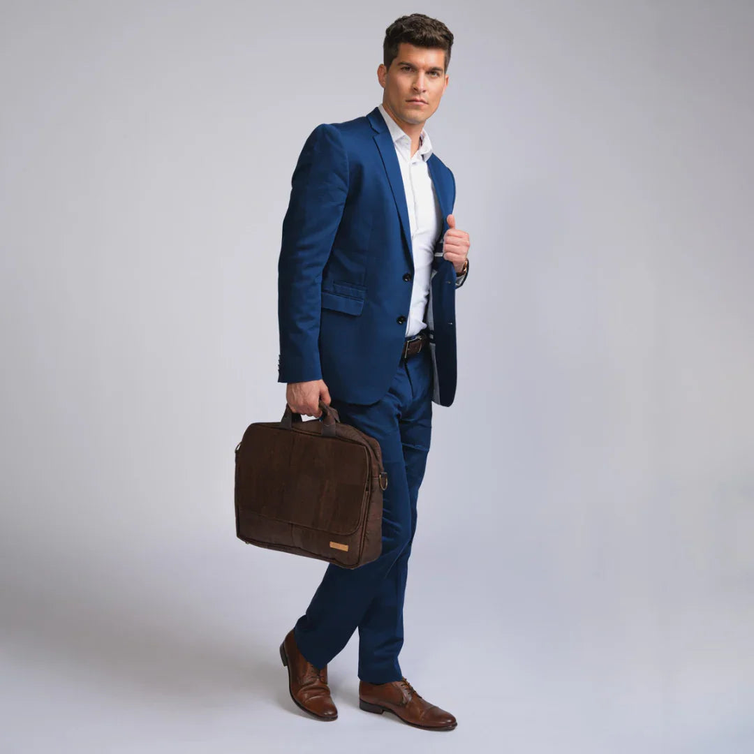 Man in blue suit carrying brown briefcase, formal fashion, neutral studio background