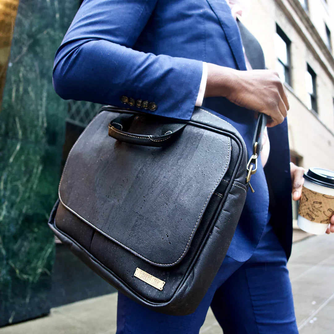 Person in blue suit carrying black vegan leather briefcase and coffee on city street