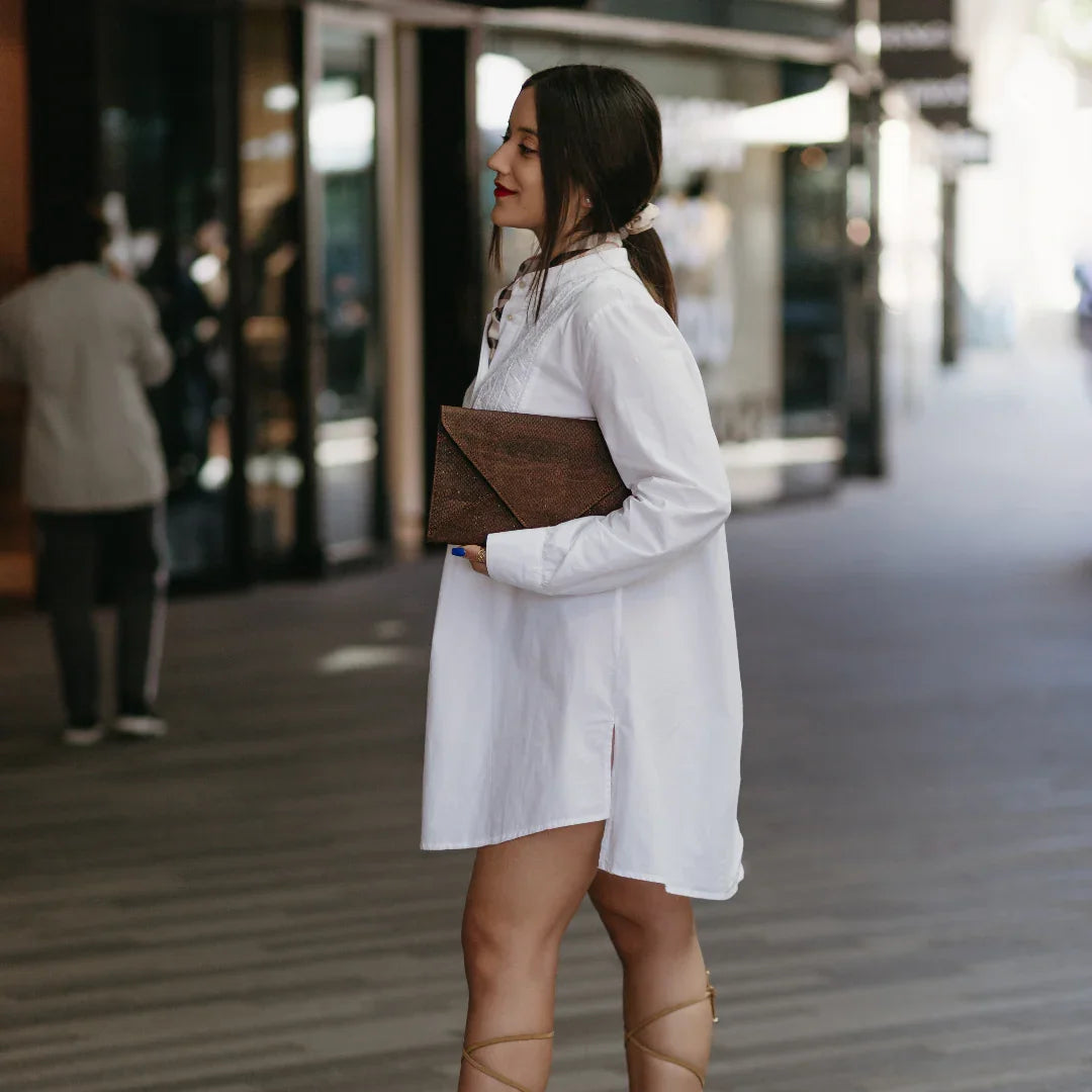 Woman in white shirt dress with brown clutch, femme-fit footwear, street style fashion