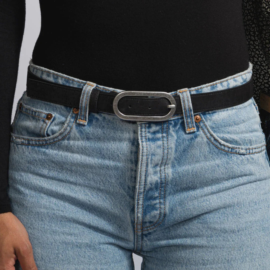 Model wearing eco-friendly black belt with silver buckle and high-waisted blue jeans