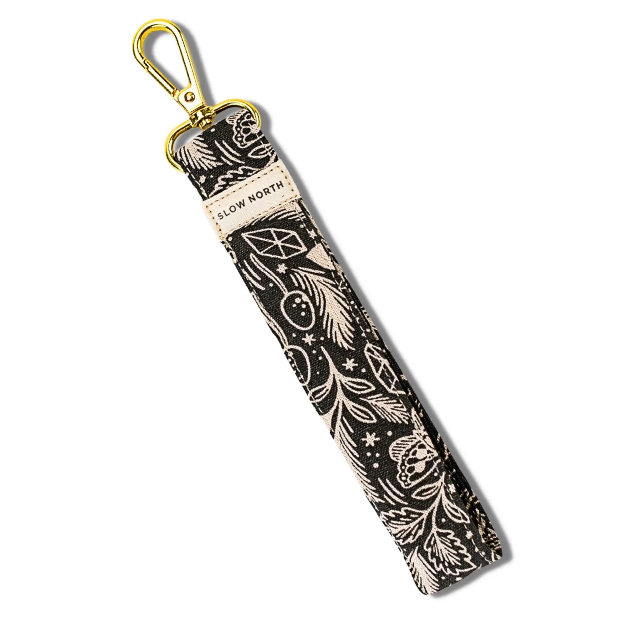 Black and white floral wristlet keychain with gold clasp and Slow North label