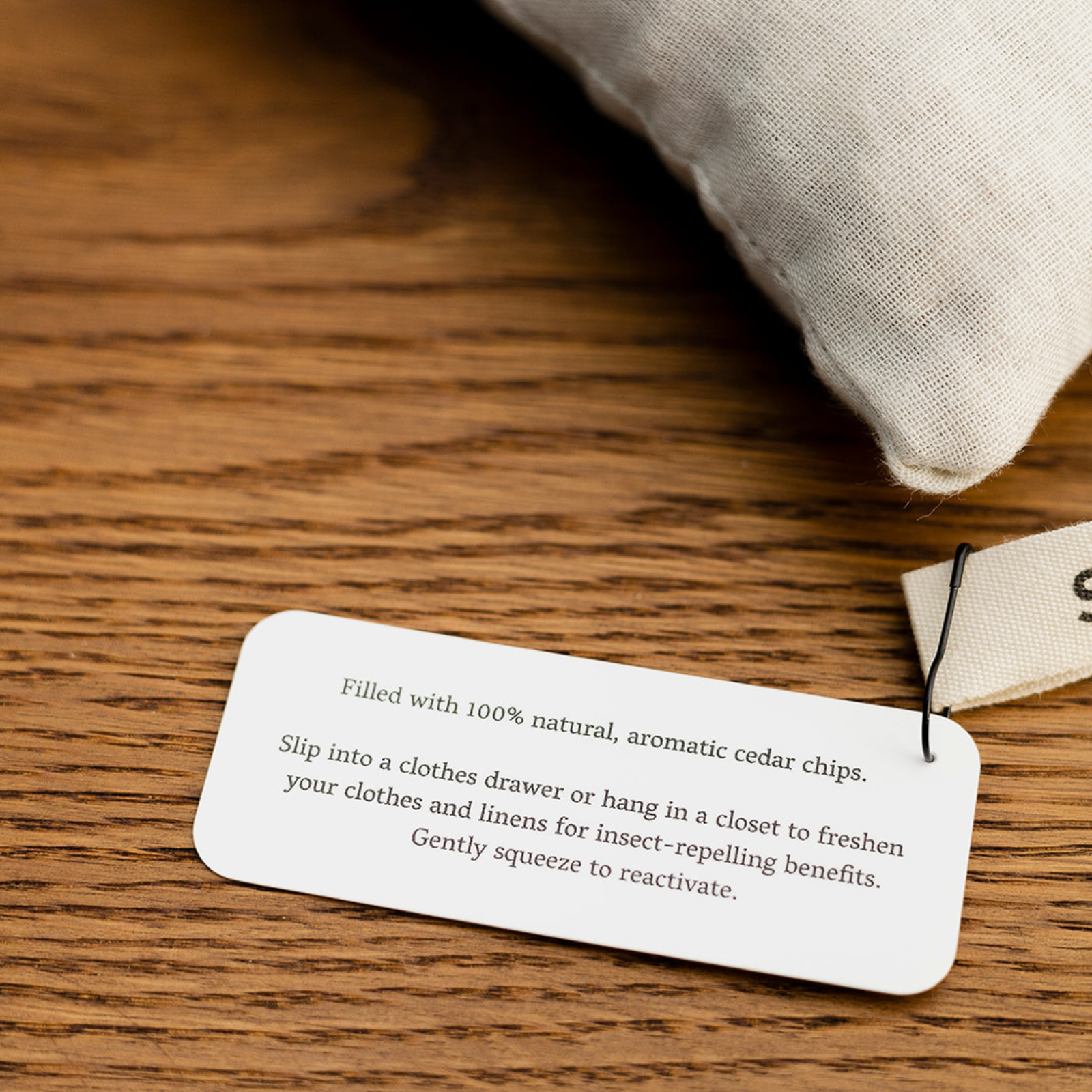 Natural cedar sachet with aromatic cedar chips and product tag on wooden surface