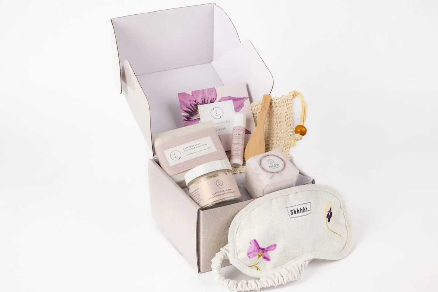 Natural lavender skincare gift box with soap, clay facial mask, lip balm, wooden brush, and floral sleep mask