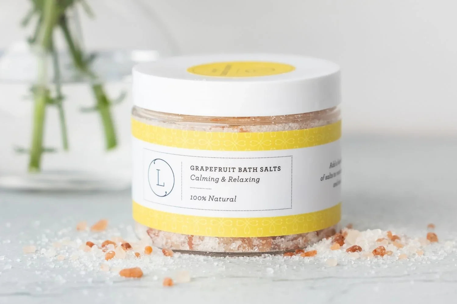 Jar of grapefruit bath salts with yellow label and scattered salt crystals on surface